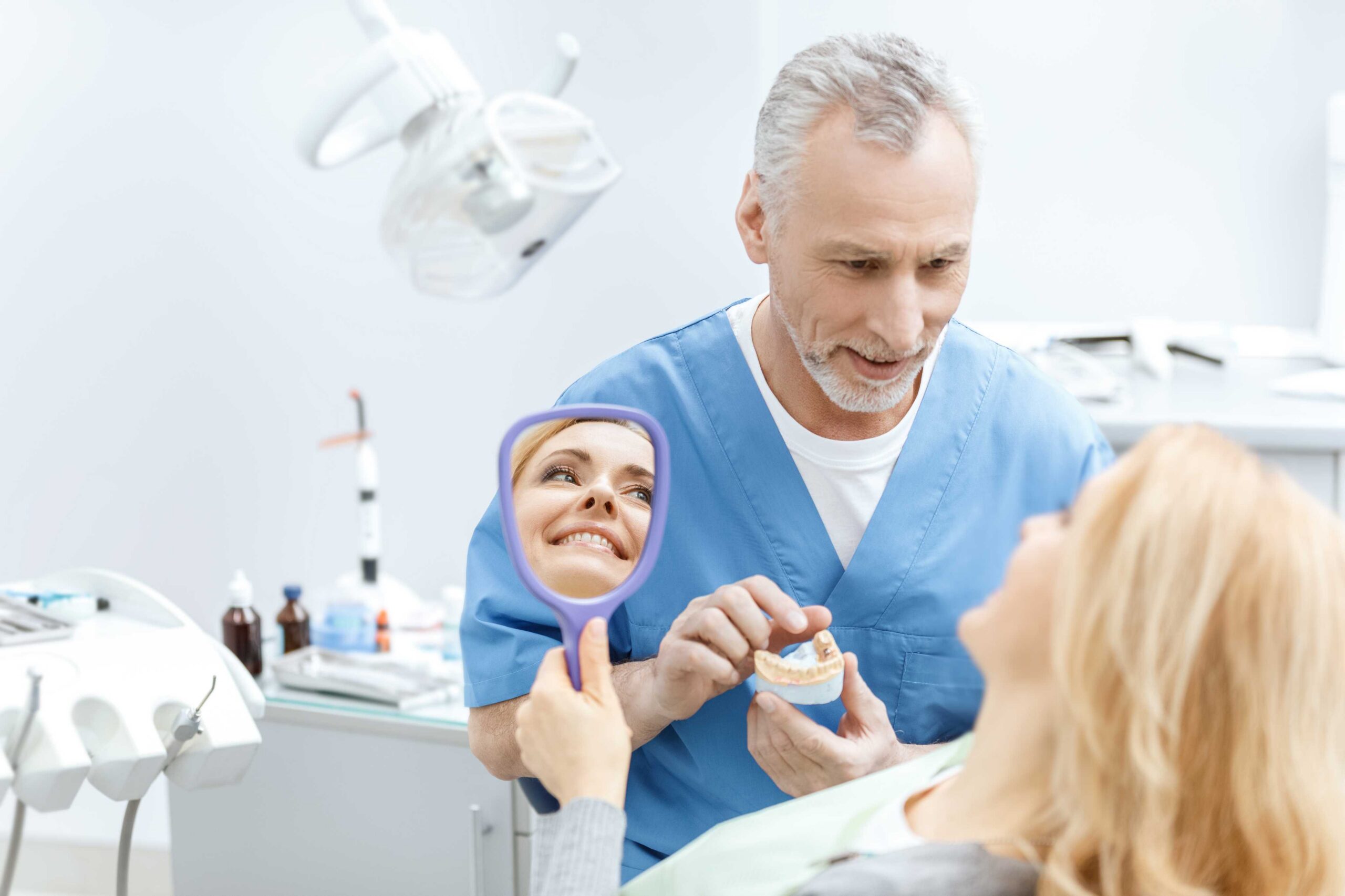 Dentist showing a dental model to a smiling patient during an oral health consultation in a modern dental clinic.